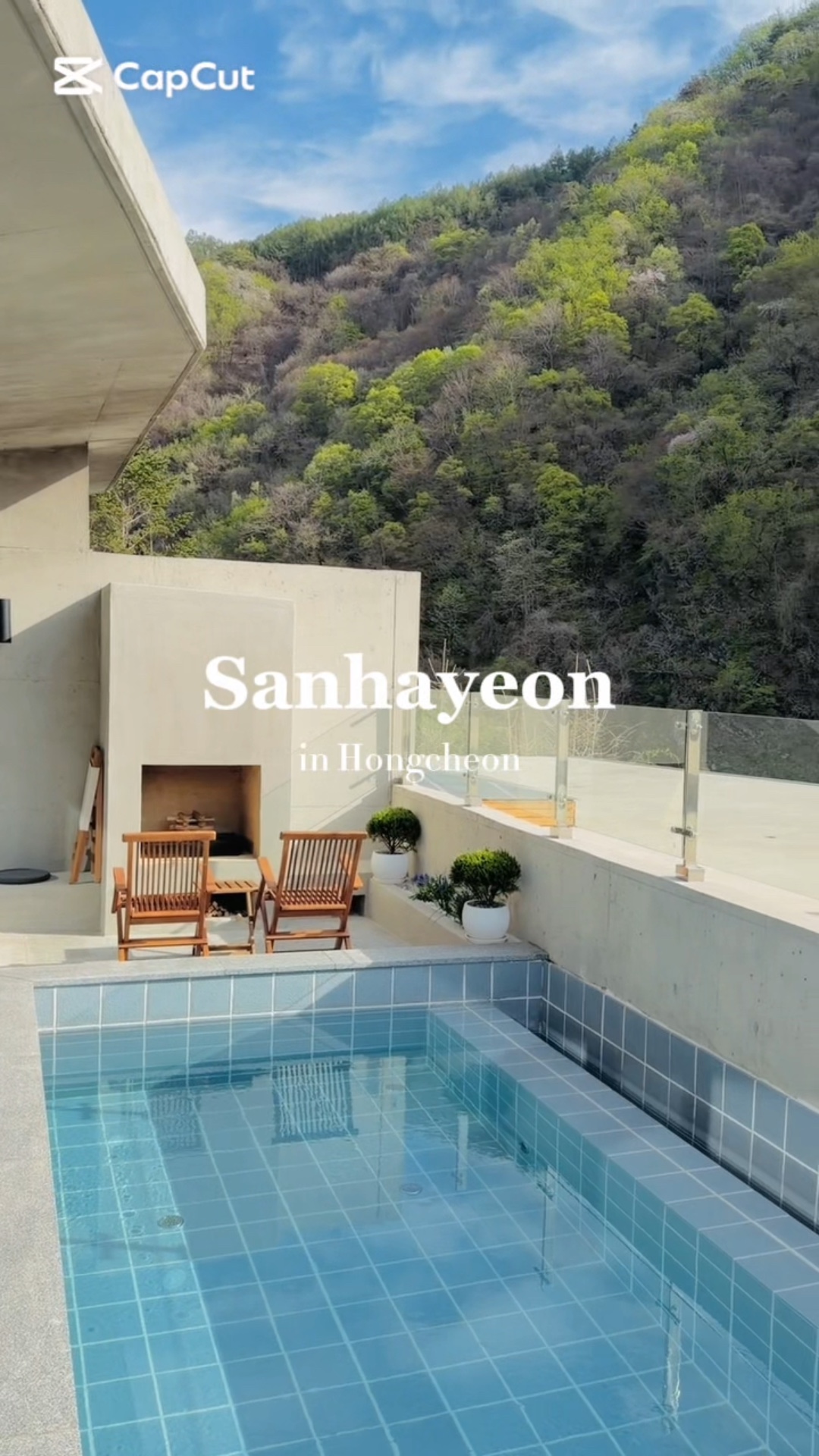 산자락 아래 야외 테라스에 위치한 수영장과 휴식용 목재 의자가 배치된 모습이다.